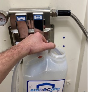 A person holding a bottle of water in front of the wall.